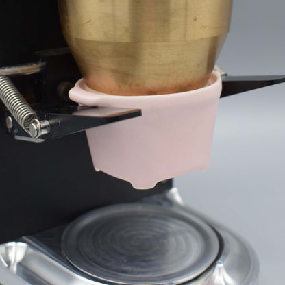 Close-up of a brass object being held by a pink clamp on a metallic surface.