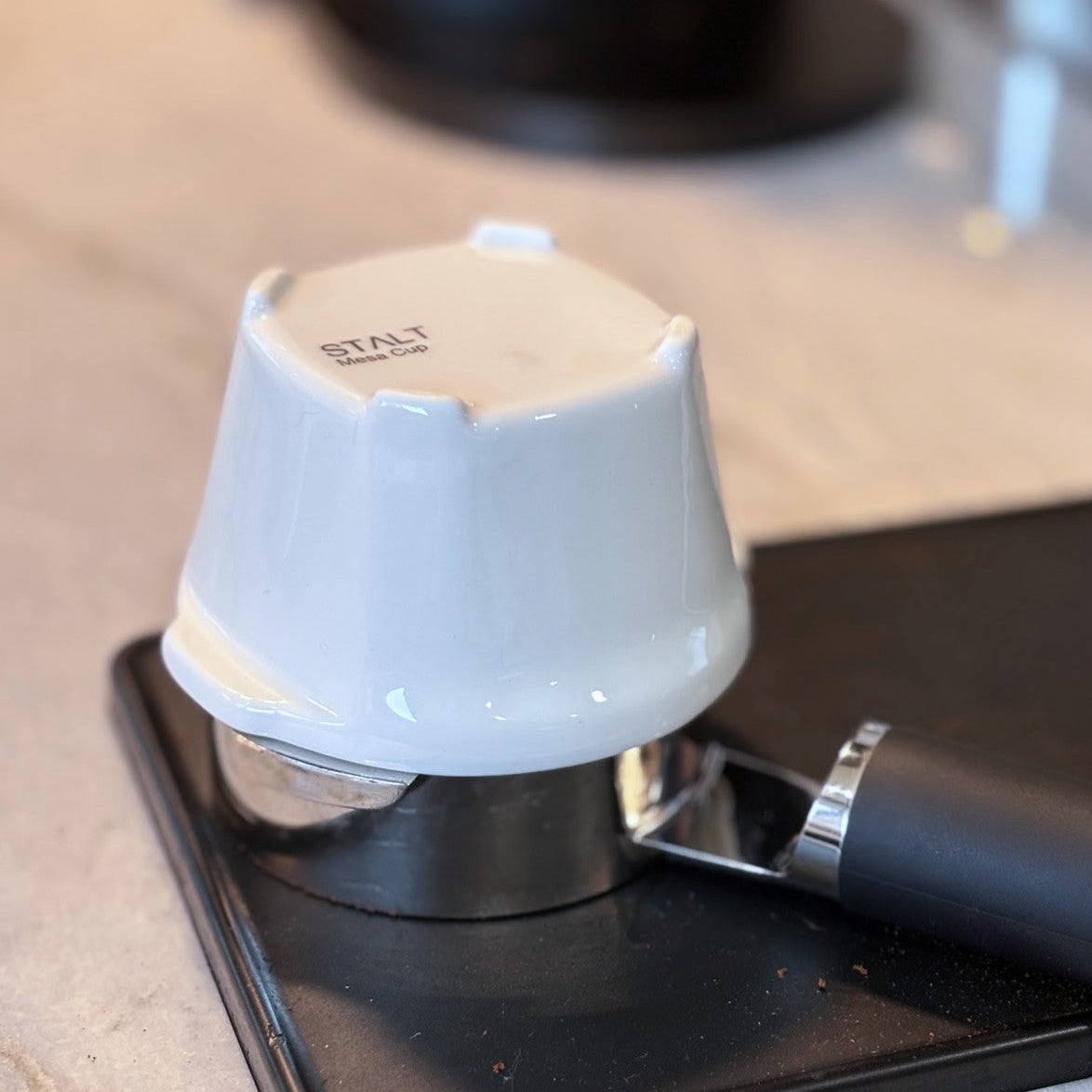 White coffee tamp on a black coffee press with 'STAL' branding.