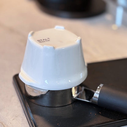 White coffee tamp on a black coffee press with 'STAL' branding.